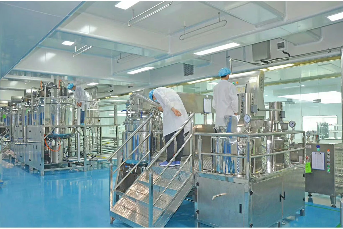 Stainless steel emulsifying tanks inside a glass-walled cleanroom at the manufacturing plant